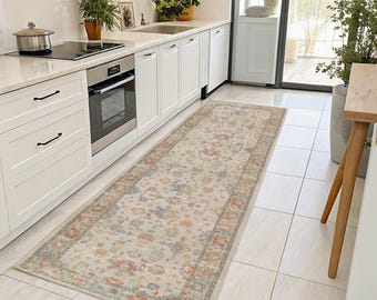 May include: A rectangular, beige runner rug with a floral pattern in shades of red, blue, and orange. The rug has a detailed border and is placed in a kitchen with white cabinets and appliances. The rug measures approximately 8 feet long.