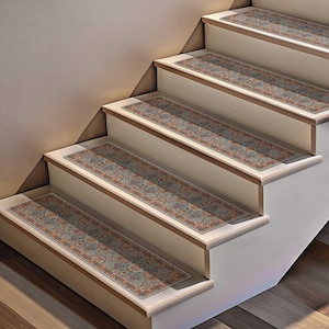 May include: Staircase with four steps, each adorned with a rectangular rug runner. The runners feature a muted blue background with a floral pattern in shades of orange, red, and cream. The steps are painted white with a light brown trim.