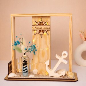 Heimathafen maritime LED Deko personalisiert – Holzrahmen mit Anker, Leuchtturm, Sand und Muscheln als Geschenk