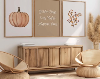 Könnte beinhalten: Drei gerahmte Drucke mit herbstlichen Motiven. Der linke Druck zeigt eine Aquarell-Illustration eines pfirsichfarbenen Kürbisses. Der mittlere Druck zeigt den Text "Golden Days Cozy Nights Autumn Vibes". Der rechte Druck zeigt eine Aquarell-Illustration eines braunen Zweigs mit kleinen roten Beeren und Blättern.