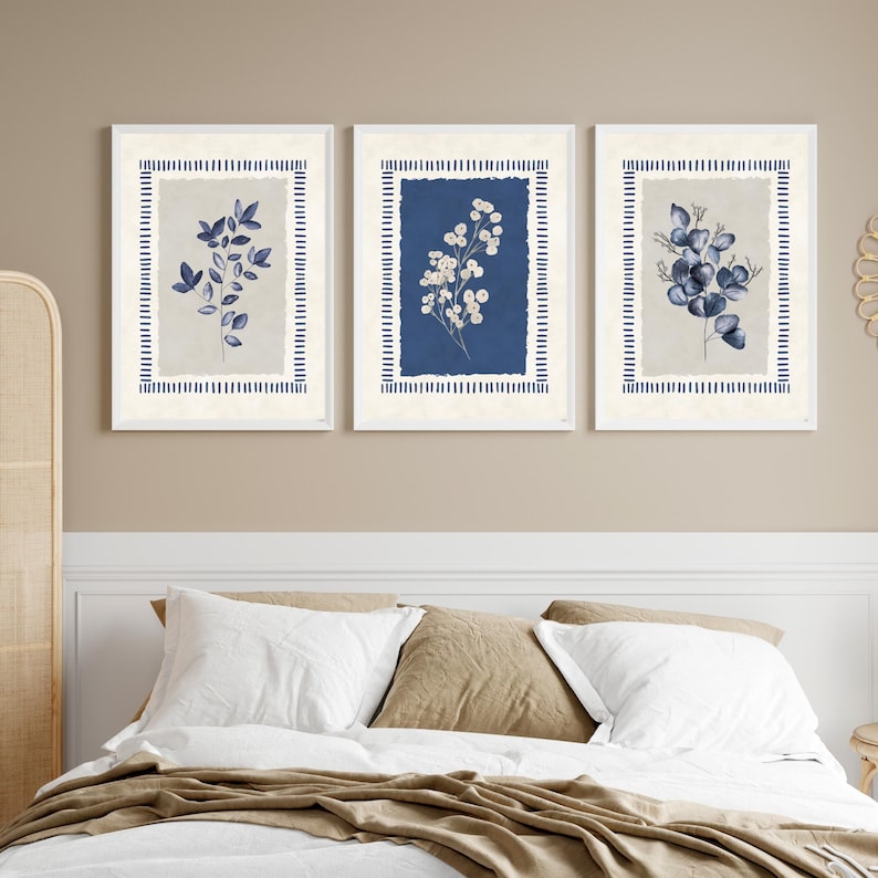 May include: Three framed botanical prints. Each print features a different floral arrangement in shades of blue and white against a neutral background. The frames are white with a blue striped border, creating a cohesive set for wall decor.