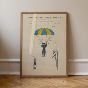 May include: Framed vintage patent illustration of a parachute. The artwork features a blue and yellow parachute canopy, a figure in a jumpsuit, and technical diagrams. The text "United States Patent Office" is visible at the top.