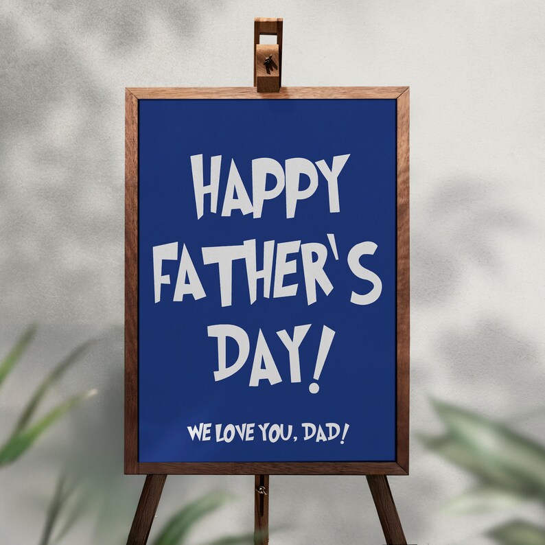 Op de afbeelding: Een houten ezel toont een blauw bord met witte tekst: "HAPPY FATHER'S DAY! WE LOVE YOU, DAD!". Het bord is omlijst met donkerbruin hout en staat tegen een neutrale achtergrond met groen.