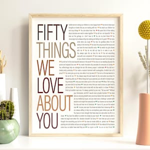 May include: A framed print with the words "FIFTY THINGS WE LOVE ABOUT YOU" in a mix of brown and burgundy fonts. The text is surrounded by a list of loving sentiments.