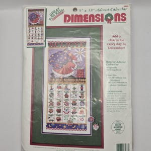 Op de afbeelding: Een Dimensions Advent Calendar kit. De kit bevat een kruissteekontwerp met een kerstman-thema, een kalenderraster en de tekst "Believe Advent Calendar". De kit meet 23 x 46 cm zonder passe-partout.