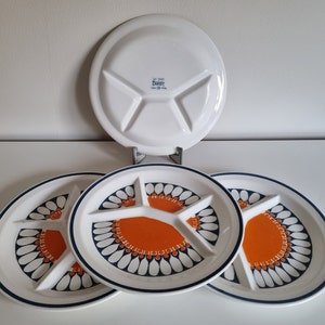Peut inclure: Trois assiettes de service divisées en céramique blanche avec un motif floral bleu et orange. Les assiettes sont divisées en quatre sections. Le texte "Saf-T-Keep Daisy Made in Hong Kong" est imprimé au dos de l'une des assiettes.