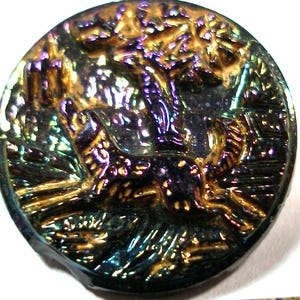 May include: A iridescent glass button with a raised design of a dog running through a forest. The button is dark blue, purple, and gold.