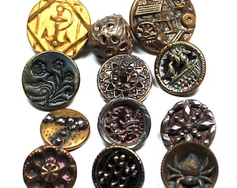 May include: A selection of antique buttons in diverse shapes and designs. The buttons display an anchor, floral patterns, a house, and a spider. Colours include gold, bronze, and dark shades, with intricate details and textures.