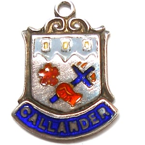 Op de afbeelding: Zilveren hanger met blauw emaille en het woord "CALLANDER" in witte letters. De hanger heeft een schild met een witte achtergrond en een blauw kruis, een rode bloem en een rood-oranje laars.