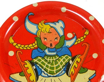 1950's tin toy tea plate. Dutch Girl ice skating graphics.  4 1/8".