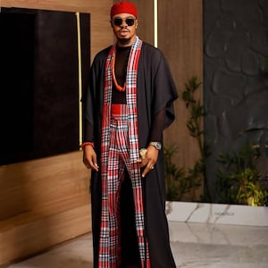 May include: A man wearing a black robe over a red and black plaid pantsuit. He is wearing a red hat and sunglasses. The text "THOM FELIX" is visible in the lower right corner of the image.