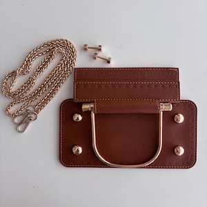 Puede incluir: Base de bolso de cuero marr&oacute;n con asa y tachuelas doradas. Tambi&eacute;n se incluye una cadena dorada y dos tornillos dorados. La base del bolso tiene forma rectangular con un borde cosido.