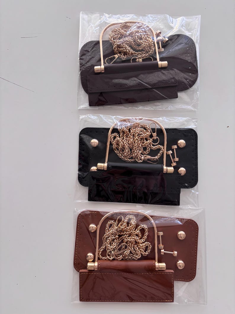 Puede incluir: Tres marcos de bolso en marr&oacute;n, negro y marr&oacute;n oscuro, cada uno con una cadena y un asa doradas. Los marcos son rectangulares con bordes redondeados y est&aacute;n empaquetados en pl&aacute;stico transparente.