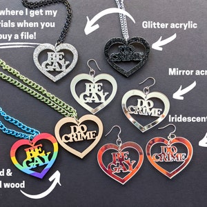 May include: A set of heart-shaped necklaces and earrings with the phrases "Be Gay" and "Do Crime" in various materials, including glitter acrylic, mirror acrylic, iridescent acrylic, wood, and painted wood.