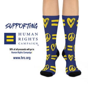 May include: A pair of blue socks with yellow peace signs, hearts, and equal signs. The socks are supporting the Human Rights Campaign. 50% of all proceeds will go to the Human Rights Campaign. www.hrc.org