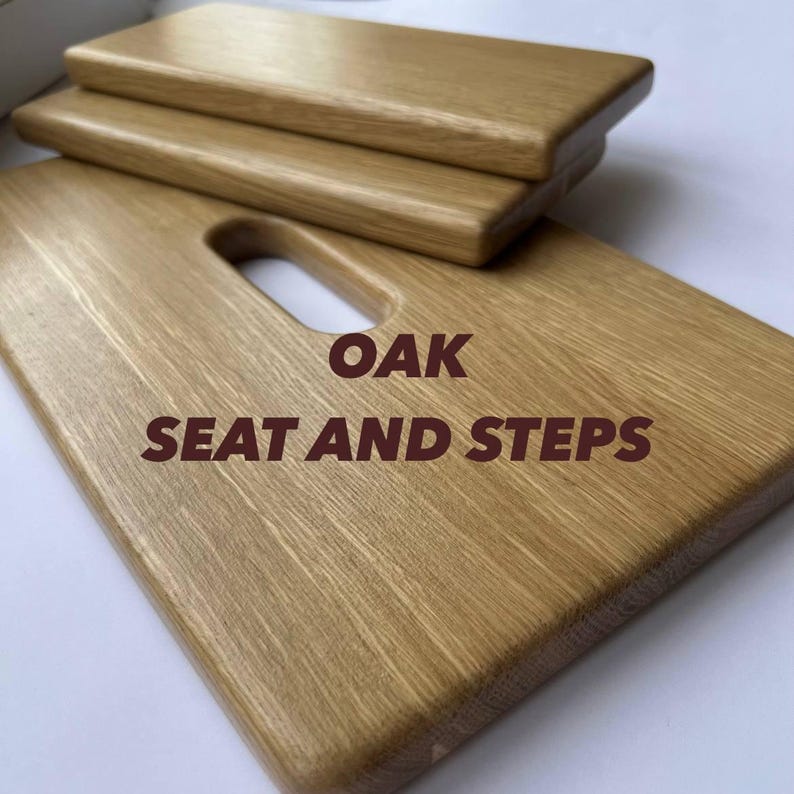 May include: Oak seat and steps, featuring a natural wood grain. The seat has a rectangular shape with a handle cutout, and two smaller steps are stacked on top. The text "OAK SEAT AND STEPS" is displayed.