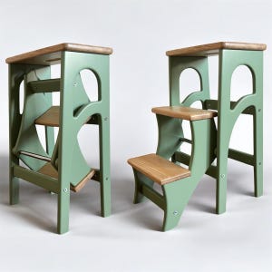 May include: Two wooden step stools in a light green hue, featuring natural wood steps and tops. The design incorporates curved supports and cut-out handles. One stool is folded, the other open. The stools are approximately 76 cm tall.