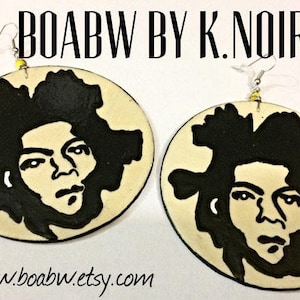 Op de afbeelding: Een paar ronde, cr&egrave;mekleurige oorbellen met zwart-wit illustraties van een gezicht. De oorbellen zijn gelabeld met "BOABW BY K. NOIR" en "www.boabw.etsy.com".