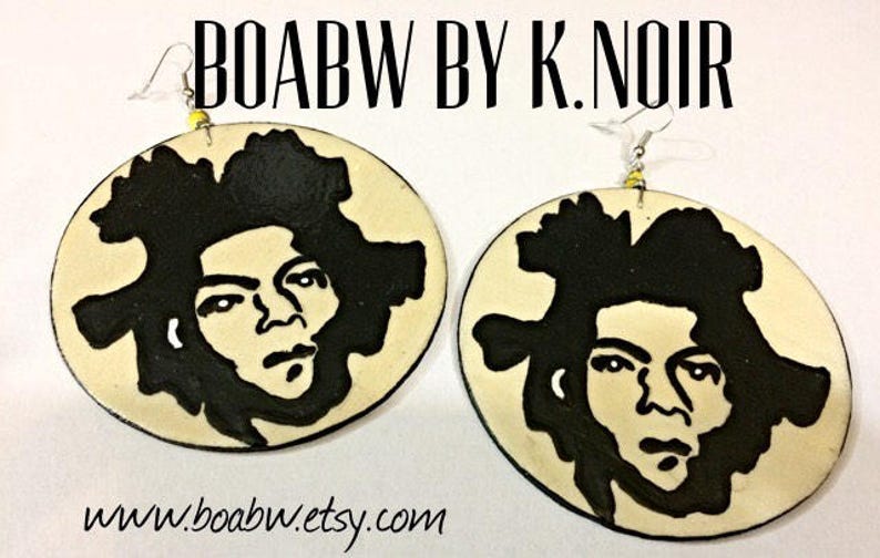 Op de afbeelding: Een paar ronde, cr&egrave;mekleurige oorbellen met zwart-wit illustraties van een gezicht. De oorbellen zijn gelabeld met "BOABW BY K. NOIR" en "www.boabw.etsy.com".