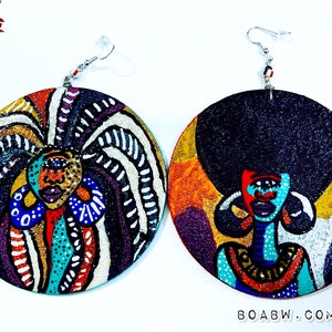 May include: A pair of large, round wooden earrings with a colorful, abstract design featuring a woman's face. The earrings are painted with bright colors, including red, blue, green, yellow, and black. The woman's face is stylized and has large eyes and a bold, colorful design. The earrings are attached to silver hooks.