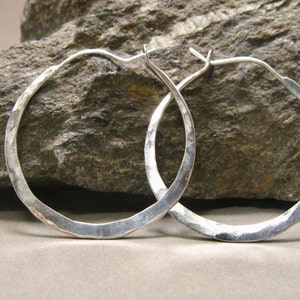 May include: A pair of silver hoop earrings with a hammered finish. The earrings are simple and elegant, and would make a great gift.