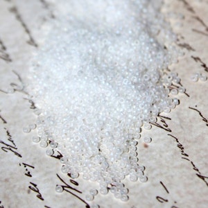 May include: A pile of small, white, round seed beads.