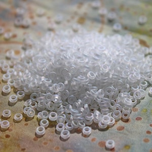 May include: A large pile of small, white, plastic rings on a patterned fabric background.