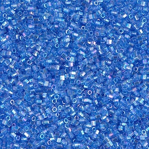 May include: A close-up view of a large quantity of small, iridescent blue glass beads. The beads are hexagonal in shape and have a slightly metallic sheen.