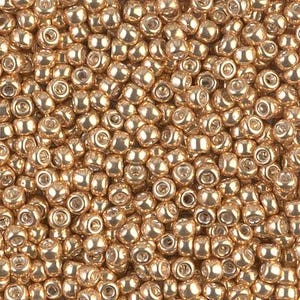 May include: A close-up image of a large quantity of small, round, gold-colored beads. The beads have a shiny, metallic finish.