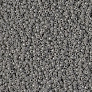 May include: A close-up view of a large quantity of small, round, gray seed beads. The beads are opaque and have a slightly shiny finish.