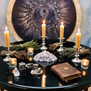 May include: A black table with a variety of items on it, including four lit candles, a pile of pink crystals, two small metal boxes, a book, and several small glass candle holders. The table is set against a backdrop of a large, circular painting with a swirling design.