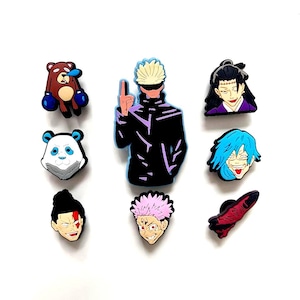 May include: A set of eight colourful rubber shoe charms featuring various anime-inspired characters, including a central figure with spiky white hair, a panda face, a brown bear, and several human-like heads with distinct hair colours and facial expressions.