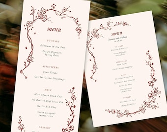 May include: Two cream-colored wedding menus with burgundy floral accents. The menus feature a list of dishes, including appetizers and main courses. The word "menu" is at the top, and the names "Jasmine and William" are also visible.