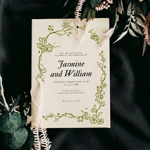 May include: A wedding invitation with the names "Jasmine and William" in elegant script. The invitation is cream-colored with a floral border and includes the date, time, and location of the ceremony.