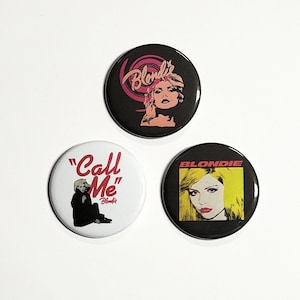 May include: Three round buttons featuring Blondie band imagery. One button has the band's logo and a portrait of a woman. Another button says "Call Me" with a seated figure. The third button has a portrait of a woman with yellow hair.