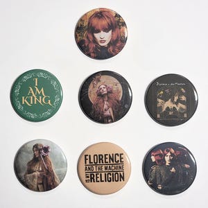 May include: A collection of seven round Florence + The Machine buttons. The buttons feature images of the band members and album art. One button has the text "I AM KING" in green. Another reads "FLORENCE AND THE MACHINE IS MY RELIGION".