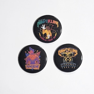 Könnte beinhalten: Drei schwarze Anstecknadeln mit einem Cartoon-Hund, der ein gelbes Hemd und eine schwarze Weste trägt. Die Nadeln zeigen den Text "POWERLINE" und "WORLD TOUR 95".