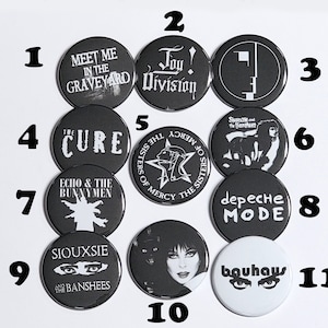 K&ouml;nnte beinhalten: Elf schwarze und wei&szlig;e runde Kn&ouml;pfe mit Bandnamen und Logos. Die Kn&ouml;pfe sind von 1 bis 11 nummeriert. Die Bands umfassen The Cure, Joy Division, Siouxsie and the Banshees, Echo and the Bunnymen, Bauhaus, Depeche Mode, The Sisters of Mercy und Meet Me in the Graveyard.