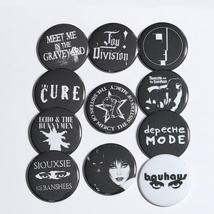 K&ouml;nnte beinhalten: Ein Set mit 10 schwarzen und wei&szlig;en runden Kn&ouml;pfen mit verschiedenen Logos von Goth-Bands aus den 80ern, darunter The Cure, Siouxsie and the Banshees, Joy Division und Bauhaus.