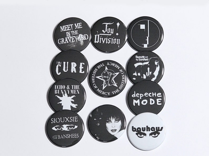 K&ouml;nnte beinhalten: Ein Set mit 10 schwarzen und wei&szlig;en runden Kn&ouml;pfen mit verschiedenen Logos von Goth-Bands aus den 80ern, darunter The Cure, Siouxsie and the Banshees, Joy Division und Bauhaus.