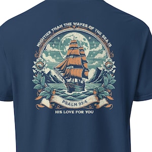 Puede incluir: Una camiseta azul marino con un gráfico de estilo vintage de un barco navegando en el océano. El gráfico incluye el texto "MIGHTER THAN THE WAVES OF THE SEA IS", "PSALM 93:4" y "HIS LOVE FOR YOU".