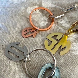 May include: Three keychains with different colored metal rings and personalized initials. The initials are "E", "S", and "M".