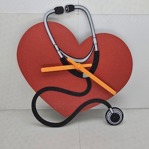 May include: Red heart-shaped clock with a black stethoscope design. The clock hands are orange.