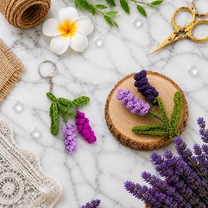 Peut inclure: Un porte-clés en crochet en forme de lavande avec des feuilles vertes et des fleurs violettes et fuchsia. Une brins de lavande au crochet est posé sur une tranche de bois. De la lavande fraîche, une fleur blanche et des ciseaux dorés sont également dans l'image.