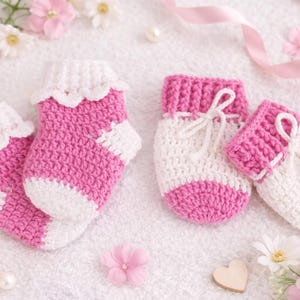 May include: Two pairs of handmade baby booties and socks. The socks are pink and white crochet with scalloped edges. The booties are white and pink with a bow. The image is decorated with pink flowers and pearls.