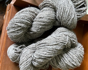 May include: Two skeins of grey yarn, each wound into a ball shape.