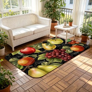 May include: A black rectangular rug with a fruit design featuring pears, grapes, and peaches. The rug has a decorative border and is placed on a wooden floor. The rug is in a sunroom with a white wicker sofa and plants.