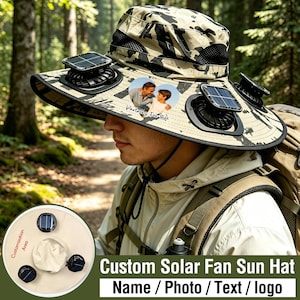 May include: A beige and black camouflage bucket hat featuring two integrated solar-powered fans on the brim. A heart-shaped patch on the front displays a photograph of two people with the text "Partners For Life" printed below the image.