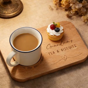 May include: A white ceramic mug with a black handle and the text "But First, Coffee" in a bold, black font. The mug is set against a blurred background, suggesting a cozy setting. The mug appears to be approximately 4 inches tall.