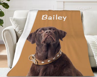 Puede incluir: Una manta personalizada con un perro marrón y un collar de cuero. El fondo es de color beige con el nombre "Bailey" en blanco. El perro mira hacia arriba. La manta está sobre un sofá blanco.